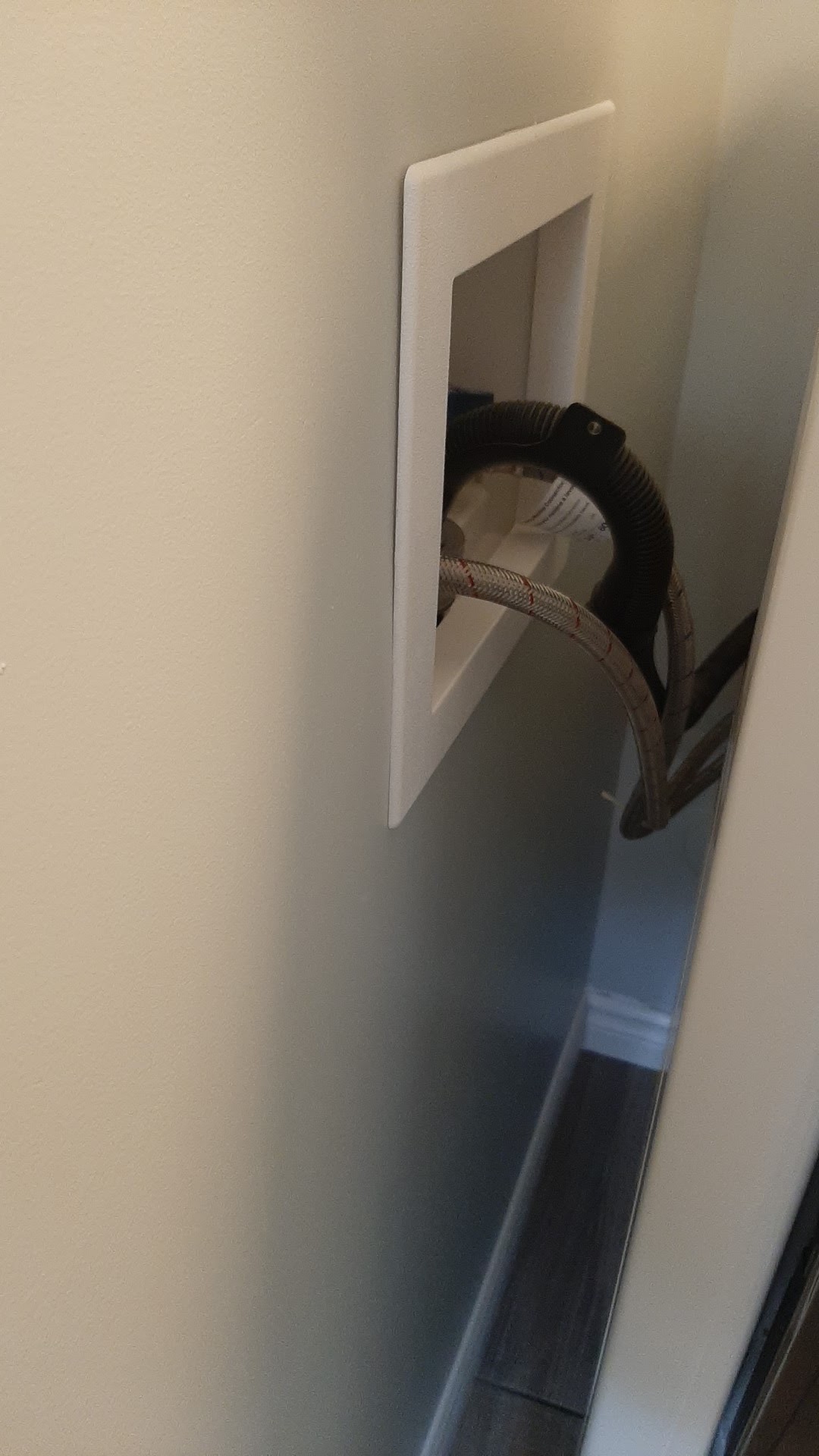 A finished recessed wall valve installation with braided supply lines